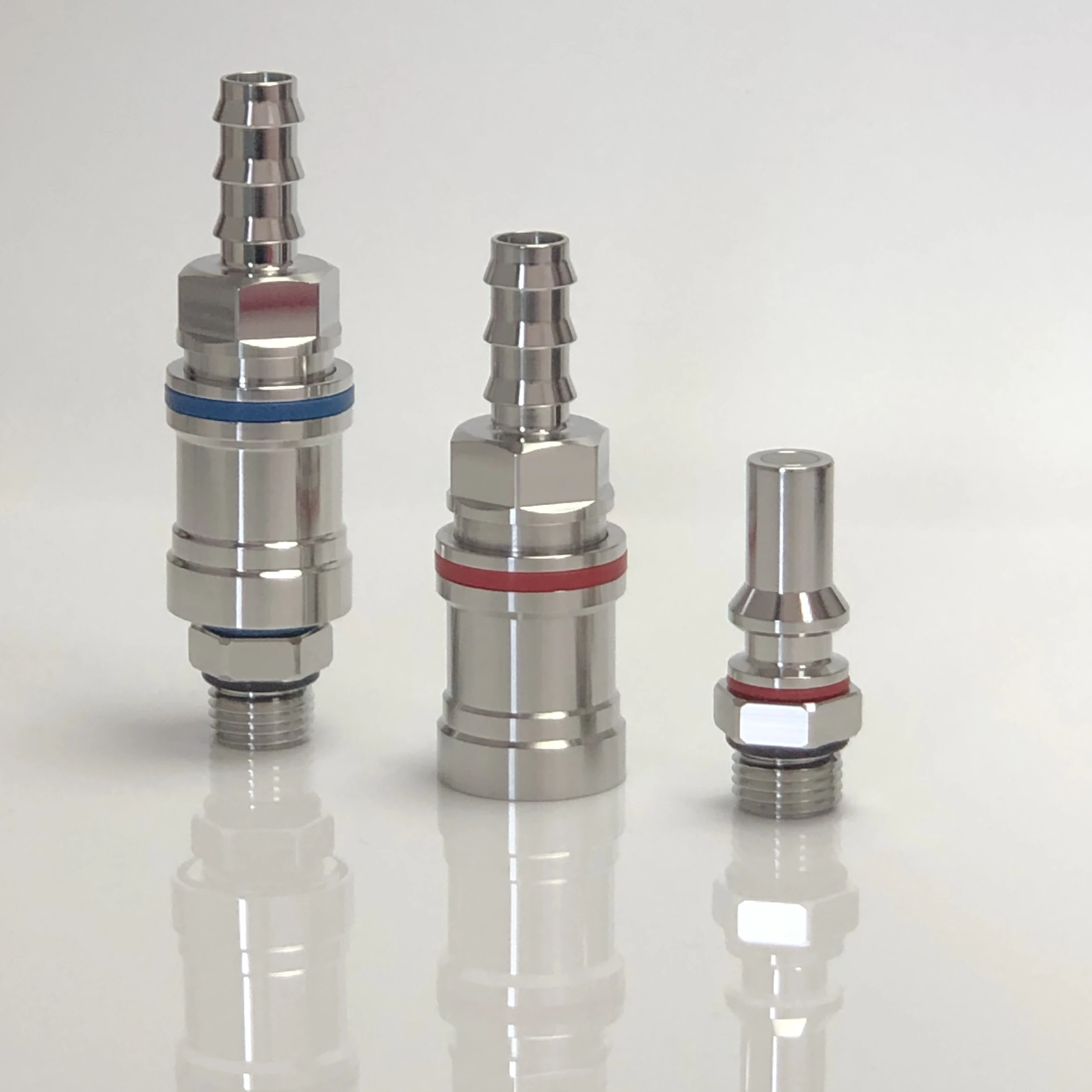 Three polished stainless steel dry-break liquid-cooling quick-disconnect fittings with hose-barb and male-thread connections
